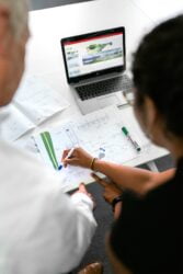 homem e mulher sentados de frente para notebook analisando projeto edados de monitoramento de obras com IA e automacao